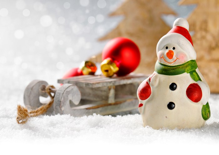 Christmas snowman with sled and ornaments in snow