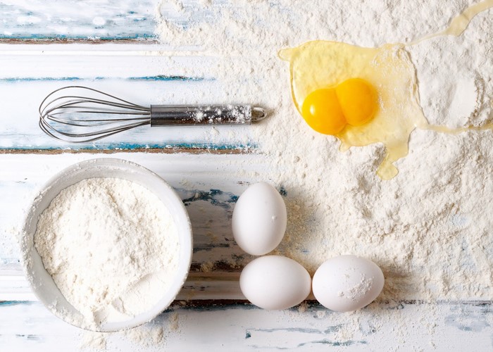 Flour, eggs, and whisk on a wooden table