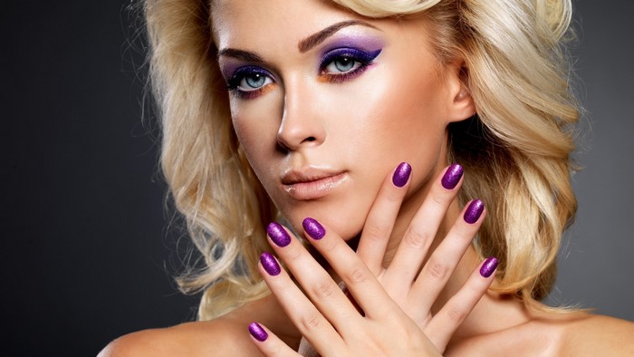 Woman with blonde hair and purple makeup and nails