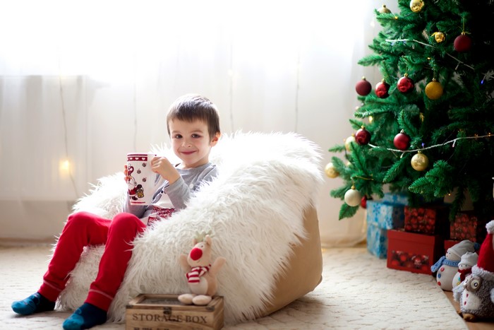 Boy with mug by Christmas tree