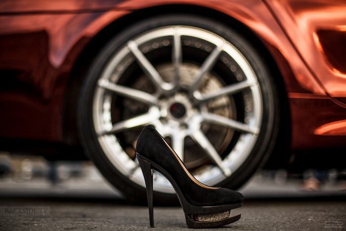 Black stiletto heel in front of a car wheel
