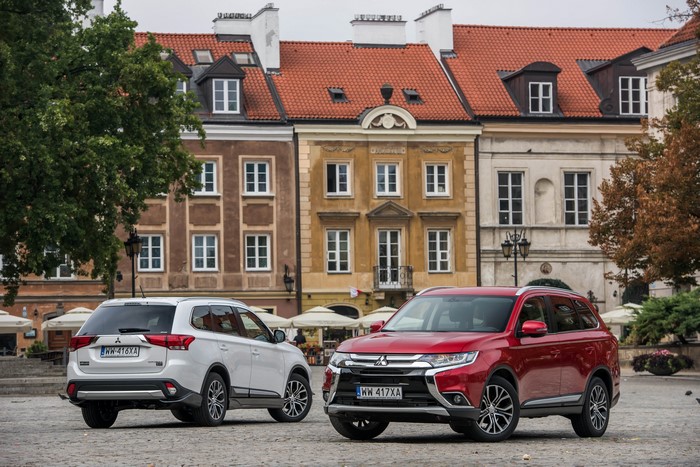 Two Mitsubishi Outlanders parked in a European city square