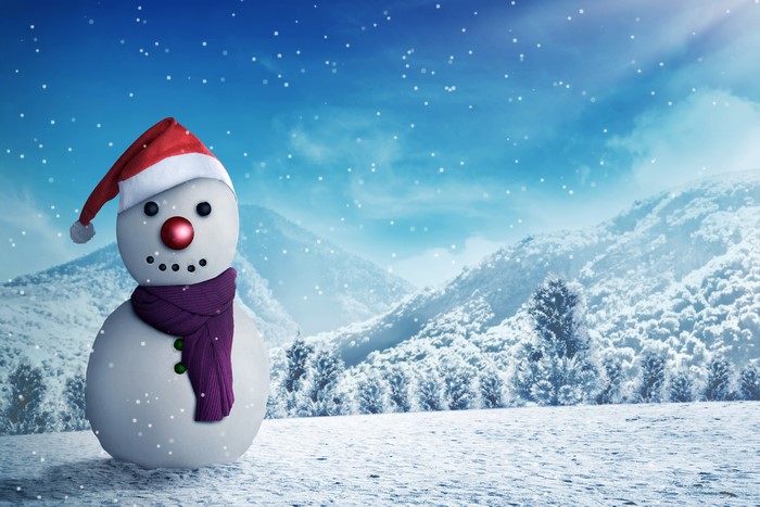 Snowman with Santa hat in snowy mountains