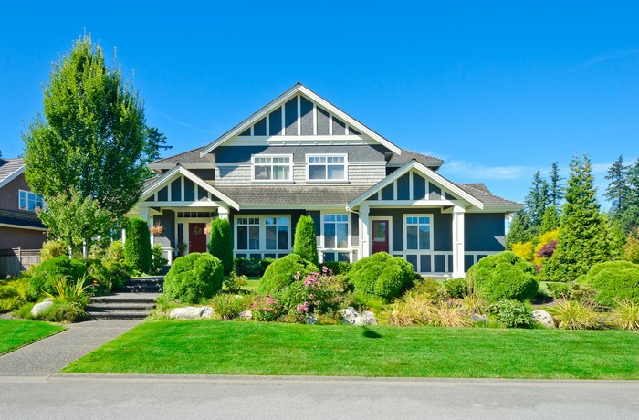 Large suburban house with manicured lawn and trees