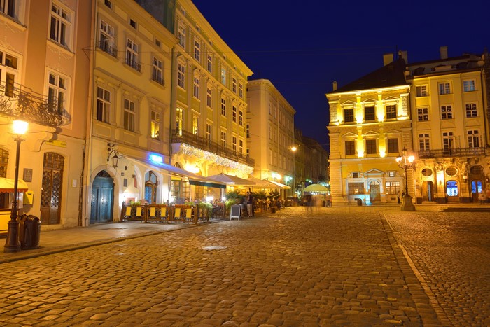 Night street in Lviv, Ukraine with illuminated buildings and cobblestone street