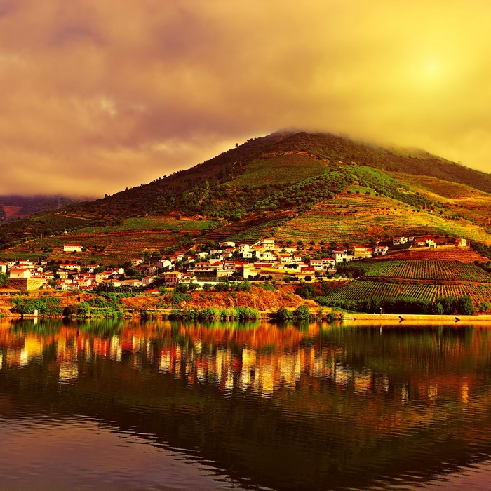 Village on terraced hillsides overlooking a river at sunset