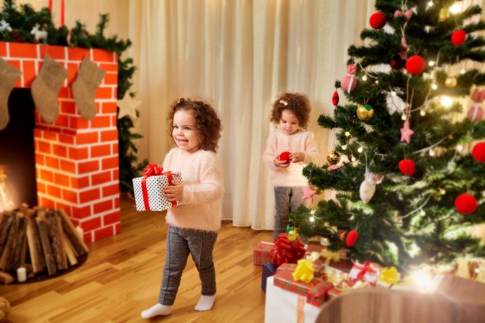 Two little girls with Christmas gifts and tree