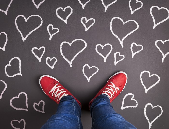 Legs in Jeans and Red Shoes on Chalk Heart Background