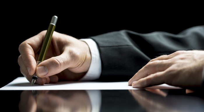 Man in Suit Writing with Pen on Paper