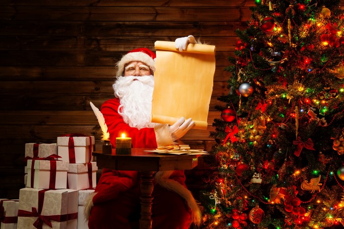 Santa Claus with a scroll by a Christmas tree