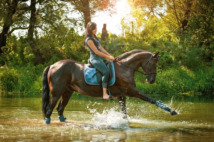 Woman riding a horse through water
