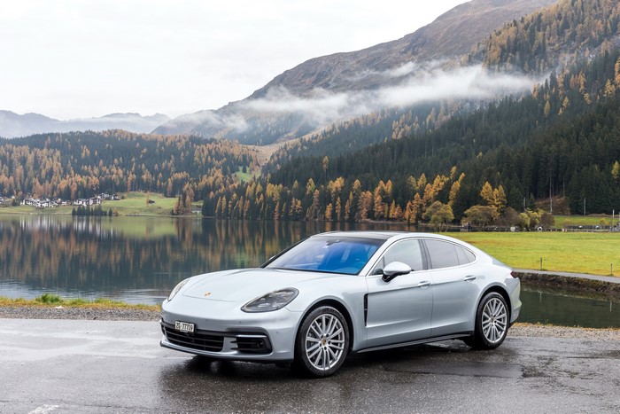 Silver Porsche Panamera 4S by a lake with mountains