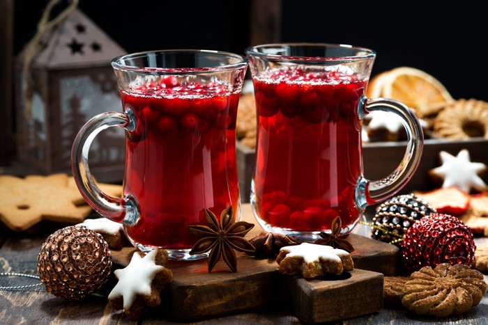 Two mugs of cranberry drink with Christmas cookies and ornaments