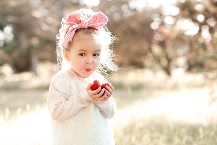 Little girl with strawberry and bowknot