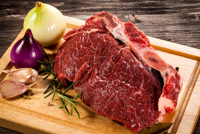 Raw Meat with Onion, Garlic, and Rosemary on Cutting Board