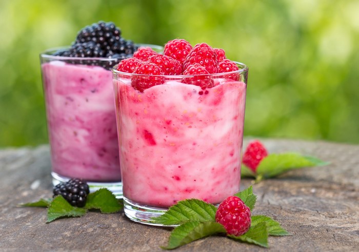 Two berry smoothies in glasses with fresh berries