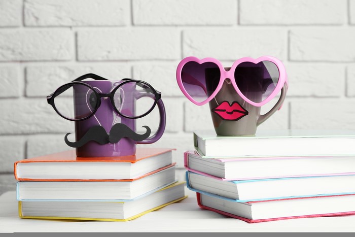 Mugs with glasses and mustache on books