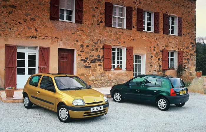Two Renault Clio cars parked in front of a stone house