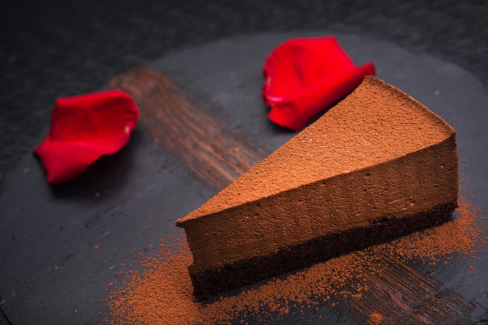 Chocolate cake slice with cocoa powder and rose petals
