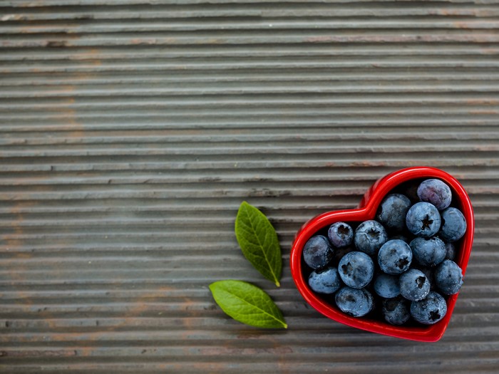 Blueberries in a heart-shaped bowl with leaves
