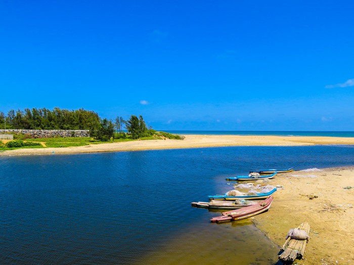 Boats on a sandy beach with a blue sky and ocean