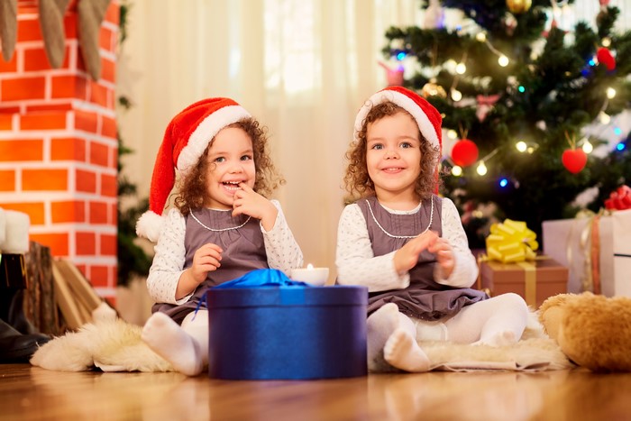 Two little girls in Santa hats with Christmas gifts