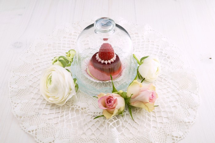 Raspberry cake under glass dome with roses and ranunculus