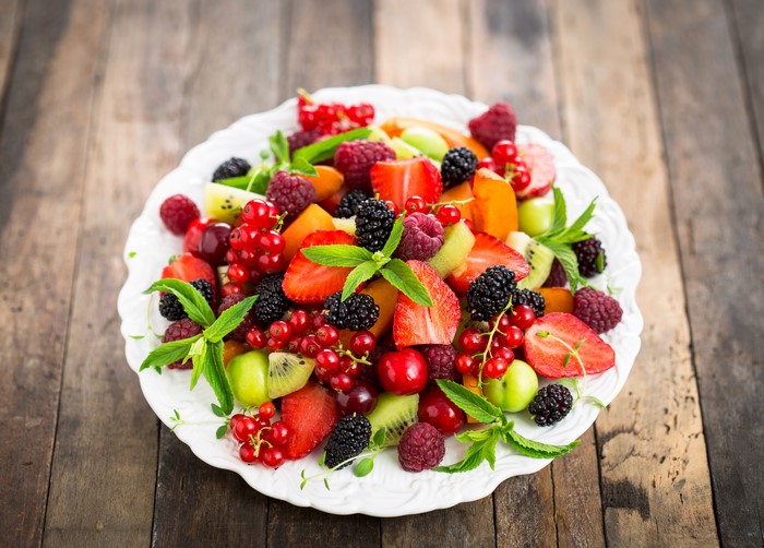 Fruit Salad on a White Plate with Wood Background