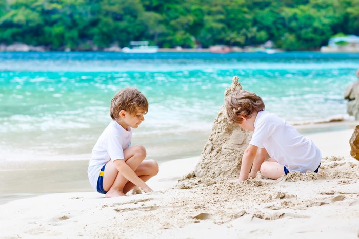 Two boys building a sandcastle on a tropical beach
