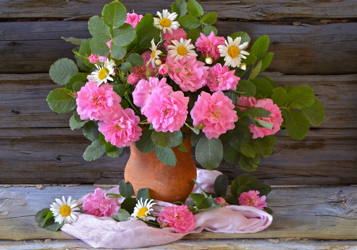 Bouquet of pink roses and daisies in a vase on wood
