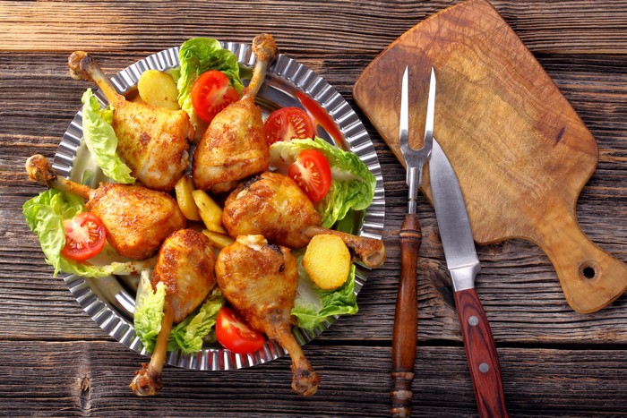 Roasted chicken drumsticks with vegetables on a platter