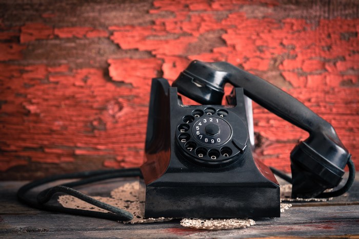 Black retro rotary telephone on a wooden surface