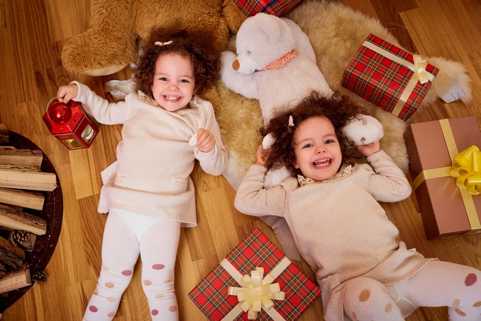 Two little girls smiling with Christmas gifts