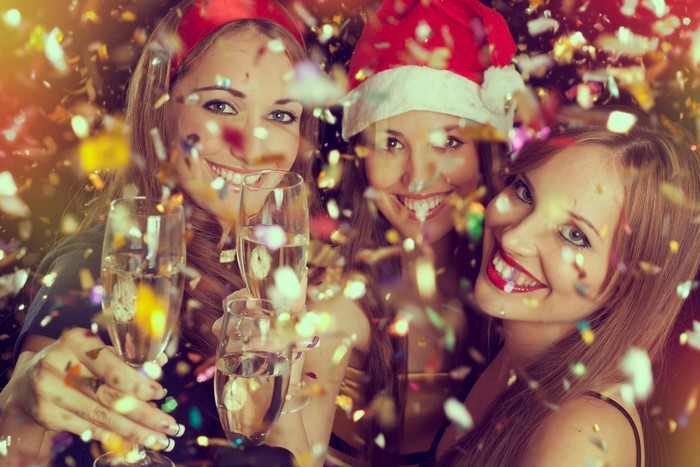 Three women celebrating with champagne and confetti