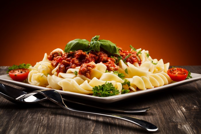 Pasta with meat sauce, tomatoes, and basil on a plate