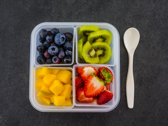 Fruit salad in a container with a spoon