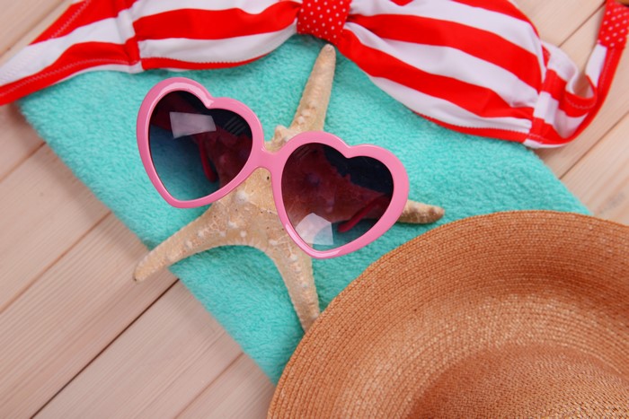 Summer beach accessories: bikini, sunglasses, starfish, hat, and towel