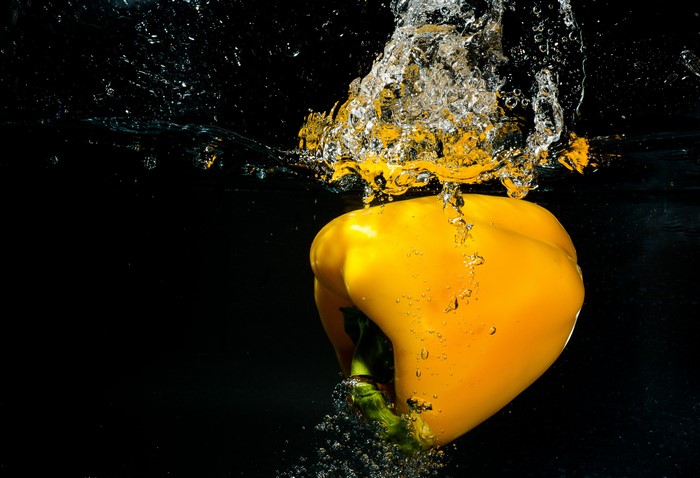 Yellow bell pepper splashing into water