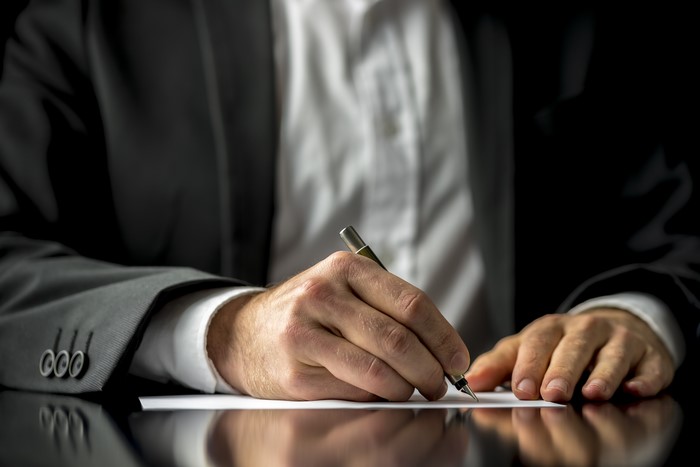 Man in Suit Writing on Paper with Ballpoint Pen