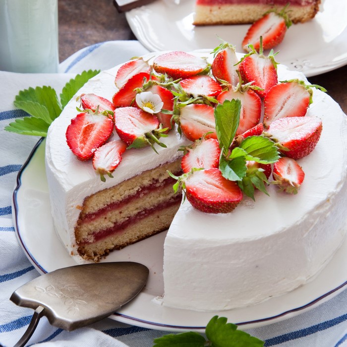 Strawberry cake with white frosting and fresh strawberries