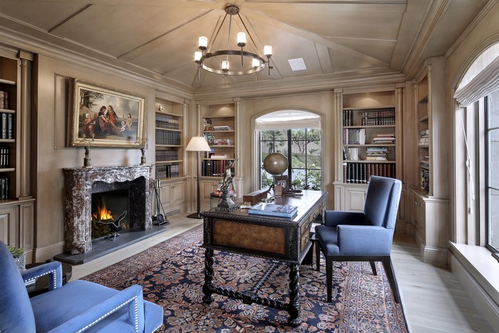Luxurious study with fireplace, desk, and armchairs