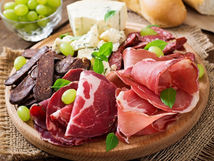 Meat and cheese platter with grapes and bread