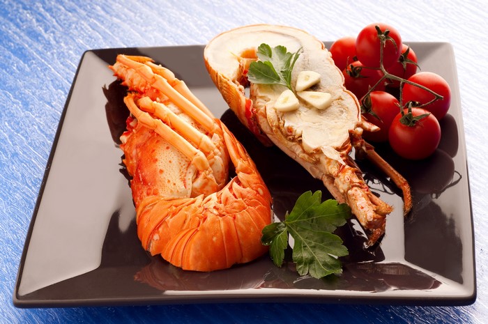 Lobster tail with tomatoes and garlic on a plate