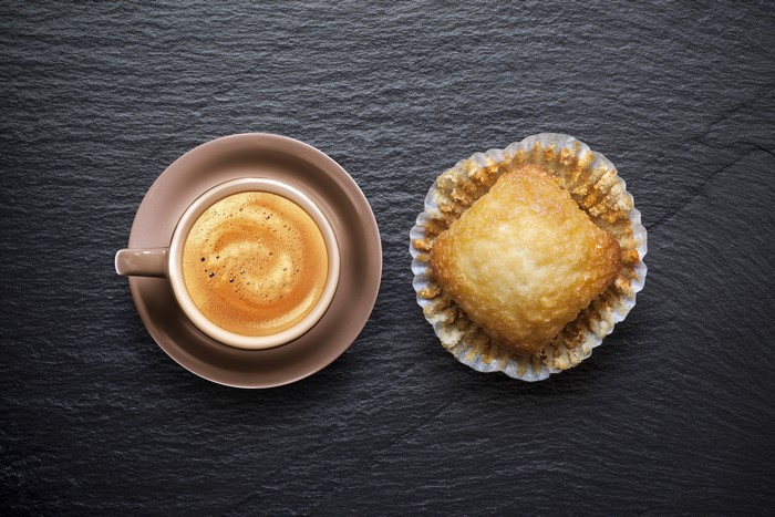 Coffee cup and pastry on black background