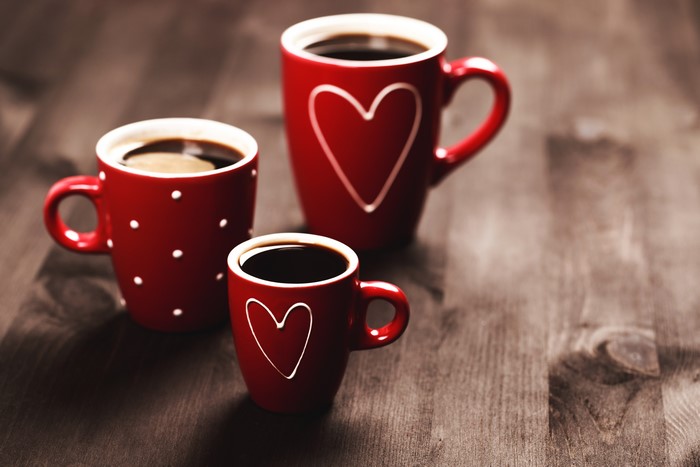 Three red mugs with coffee and hearts