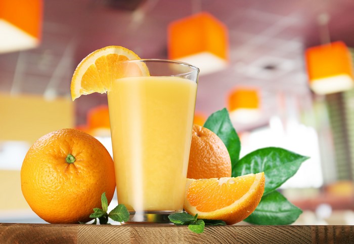Orange juice in a highball glass with oranges