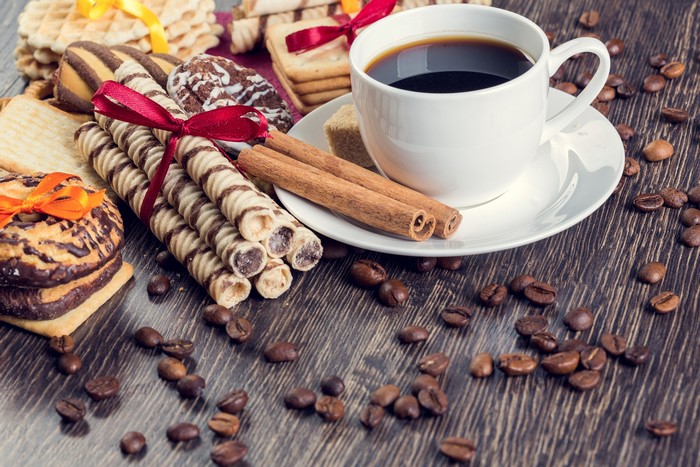 Coffee cup with pastries and cinnamon sticks