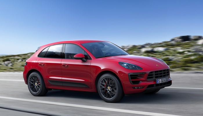 Red Porsche Macan GTS driving on a road
