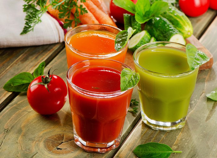 Three glasses of vegetable juice with fresh vegetables