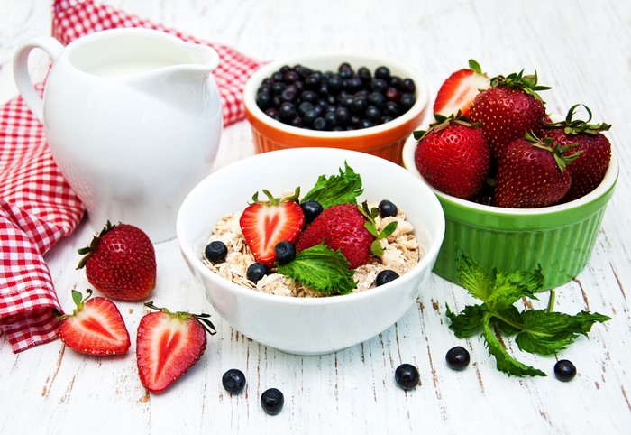 Muesli with strawberries and blueberries in a bowl with milk jug